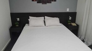 Una habitación de hotel con una cama grande, dos mesitas de noche y una obra de arte colgada en la pared.
