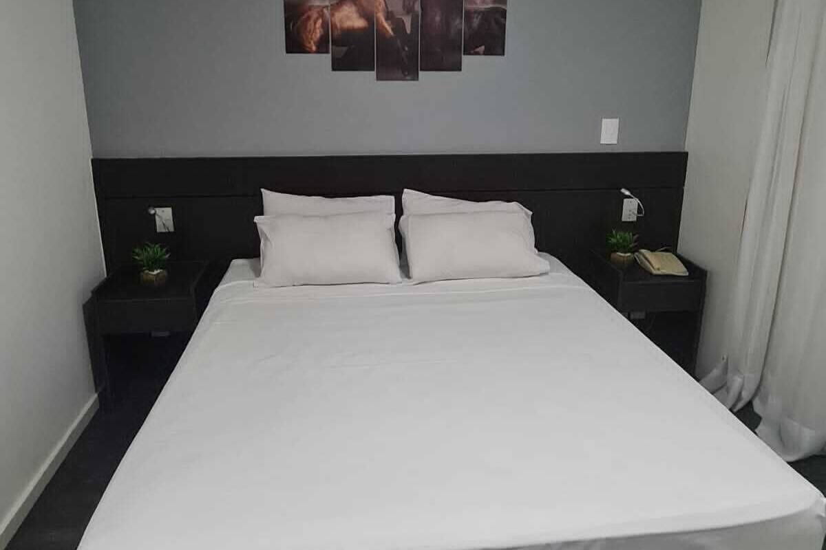 A hotel room with a large bed, two bedside tables, and a wall-mounted artwork.