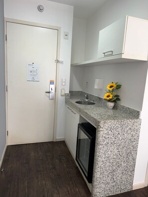 A compact kitchen with a granite countertop, a built-in oven, and a small sink. - Suites Pampulha Hotel (Belo Horizonte)