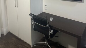 Una habitación con escritorio, silla, televisor y armario.