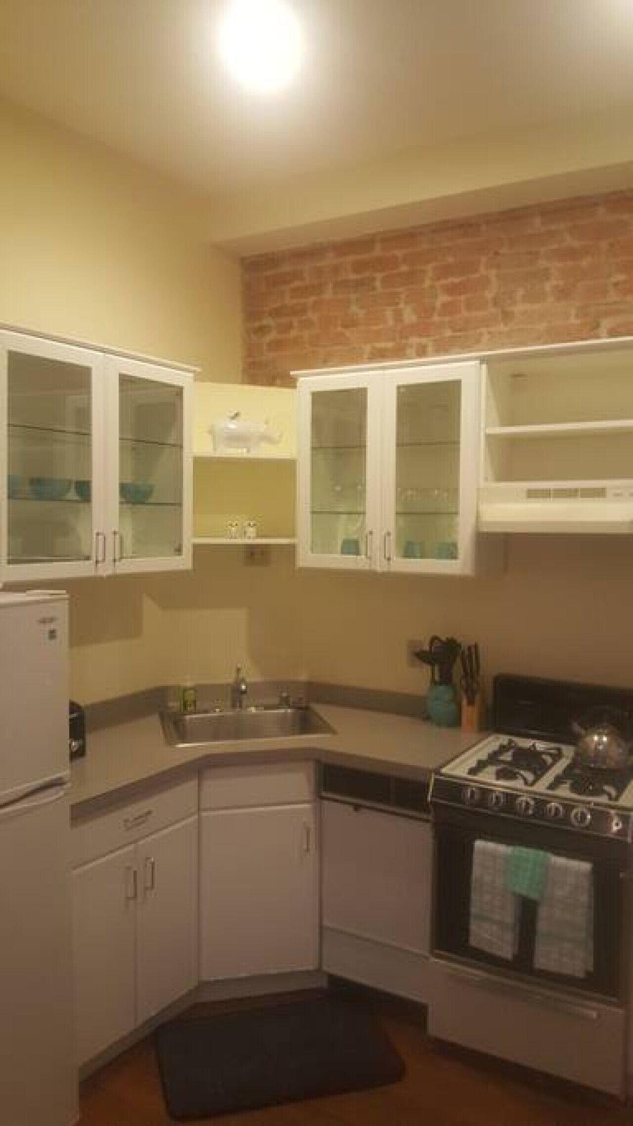 A compact kitchen with white cabinets, a sink, a stove, and a refrigerator.
