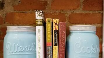 Two light blue Mason jars on a shelf with books in between.