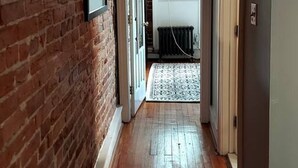 A hallway with a brick wall, wooden floor, and a radiator.