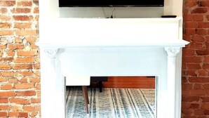 A fireplace with a television mounted above it, set against a brick wall.