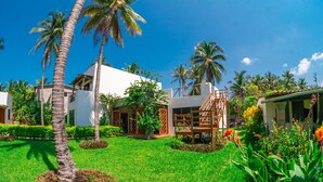 A resort with a white building, palm trees, and a well-maintained lawn.