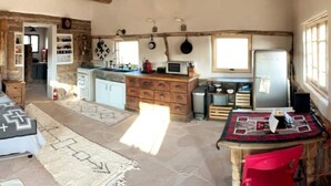 A rustic kitchen with wooden cabinets, a microwave, and hanging pots. - Luscious Adobe Studio in Gorgeous Abiquiu! (Abiquiu)