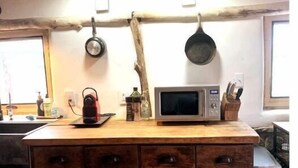 A kitchen with a wooden island, a microwave, hanging pots, and a rustic design. - Luscious Adobe Studio in Gorgeous Abiquiu! (Abiquiu)