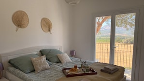 Une chambre avec un lit, des oreillers, un plateau avec le petit-déjeuner et une vue sur l’extérieur.