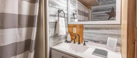 A bathroom with a white sink, a mirror, a towel ring, and a wooden accent wall.