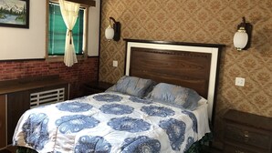 A bedroom with a bed, a window with curtains, a wall-mounted lamp, and a patterned wallpaper. - Heritage place Hotel  (Gravelbourg)