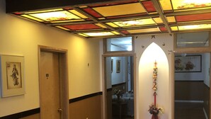 A hallway with a striped carpet, a wooden door, a stained glass ceiling, and a small alcove with a vase. - Heritage place Hotel  (Gravelbourg)