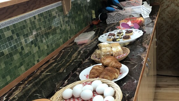A buffet counter with various food items, including eggs, pastries, and bread. - Heritage place Hotel  (Gravelbourg)