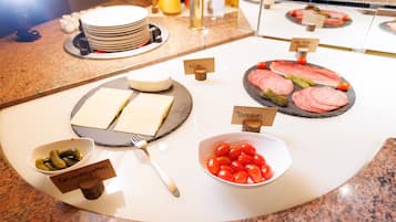 Un buffet con diversi alimenti, tra cui formaggio, pomodori e sottaceti.
