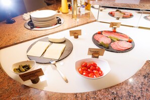 A buffet with various food items including cheese, tomatoes, and pickles. - Naturhotel Blaubach (Blaubach)