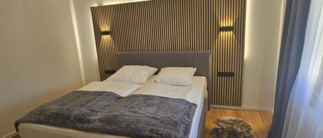 A modern bedroom with a large bed, a wooden slat headboard, and a fluffy rug.