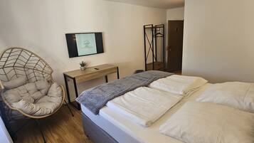 A bedroom with a bed, a desk, a chair, and a wardrobe.
