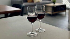 A modern living room with a sofa, coffee table, and two wine glasses on a table.