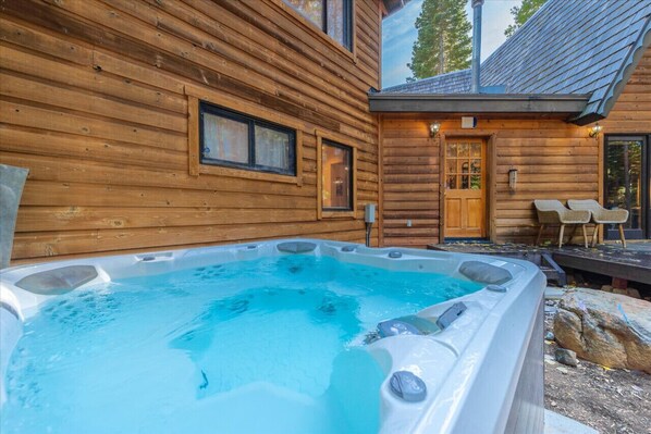 Relax in a cabin with a hot tub, large window, and comfortable seating area.