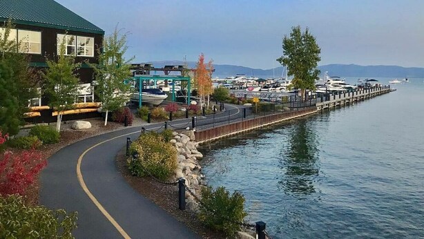 Una propiedad frente al mar con un paseo pavimentado, un muelle y un puerto deportivo con barcos.