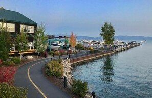 A waterfront property with a paved walkway, a dock, and a marina with boats.