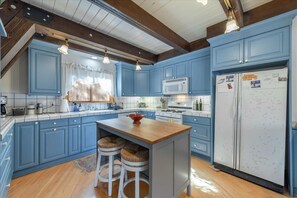 Enjoy cooking in this well-equipped kitchen with a refrigerator, microwave, and wooden island with stools.