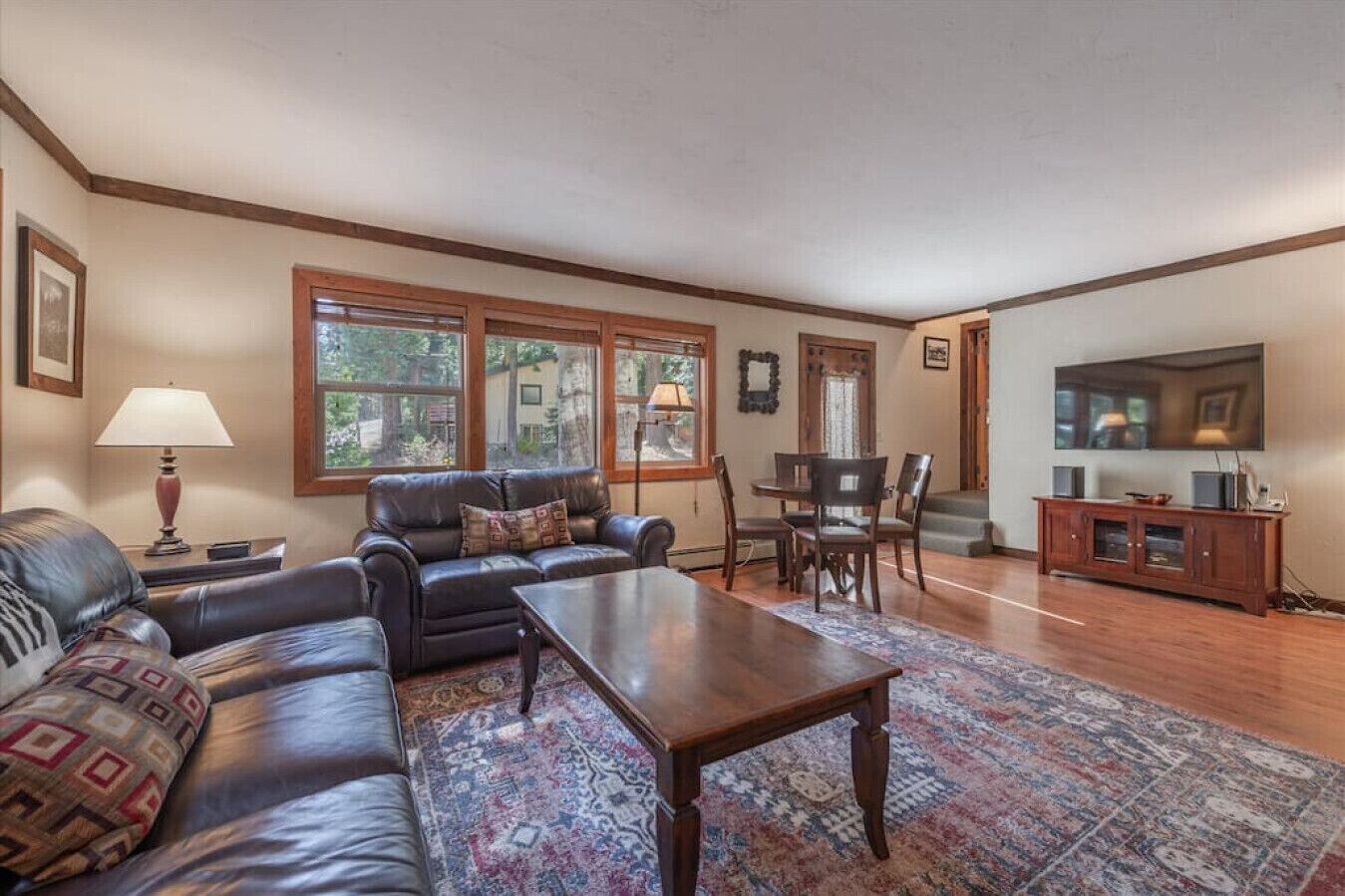 A living room with a sofa set, a coffee table, a dining table with chairs, a TV, and a cabinet.