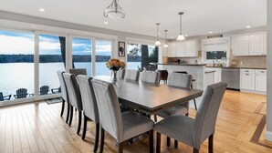Une cuisine moderne avec des meubles blancs, un grand îlot central et une vue sur un lac.