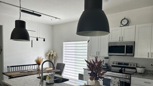 A modern kitchen with white cabinetry, a granite countertop, a built-in oven, a microwave, and a sink. - Peaceful Ocala Home • Fire Pit • 20 Min to World Equestrian Center (Ocala)