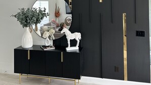 A modern living room with a black and gold console, a round mirror, and decorative items including a white vase and a white horse sculpture. - Peaceful Ocala Home • Fire Pit • 20 Min to World Equestrian Center (Ocala)