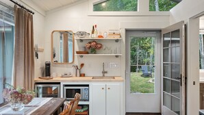 Moderni keittiö, jossa on puinen työtaso, valkoiset kaapit, sisäänrakennettu uuni ja suuri ikkuna, josta avautuu näkymä puutarhaan.