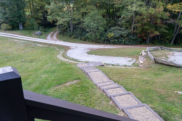 A gravel path leading through a grassy area with a wooden fence and trees in the background.