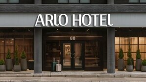 L’extérieur de l’hôtel Arlo se distingue par sa façade moderne, ses grandes fenêtres et son numéro d’entrée bien visible, le 88.