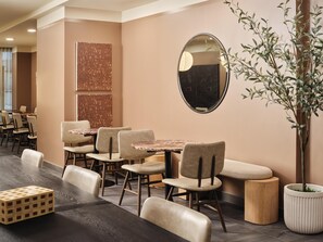 A dining area with round tables, cushioned chairs, a large mirror, and a potted plant. - Arlo, BW Signature Collection (Ottawa)
