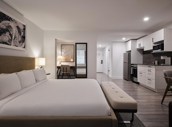 A modern hotel room with a large bed, a desk, a chair, and a kitchenette. - Arlo, BW Signature Collection (Ottawa)