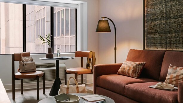 Un salon confortable avec un canapé, des fauteuils, une table et une lampe.