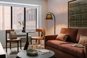 A cozy living area with a sofa, chairs, a table, and a lamp. - The Ora Hotel, BW Signature Collection (Ottawa)