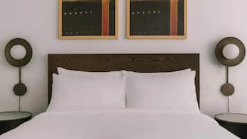 Una cama con cabecera de madera, dos apliques redondos en la pared y dos cuadros enmarcados.