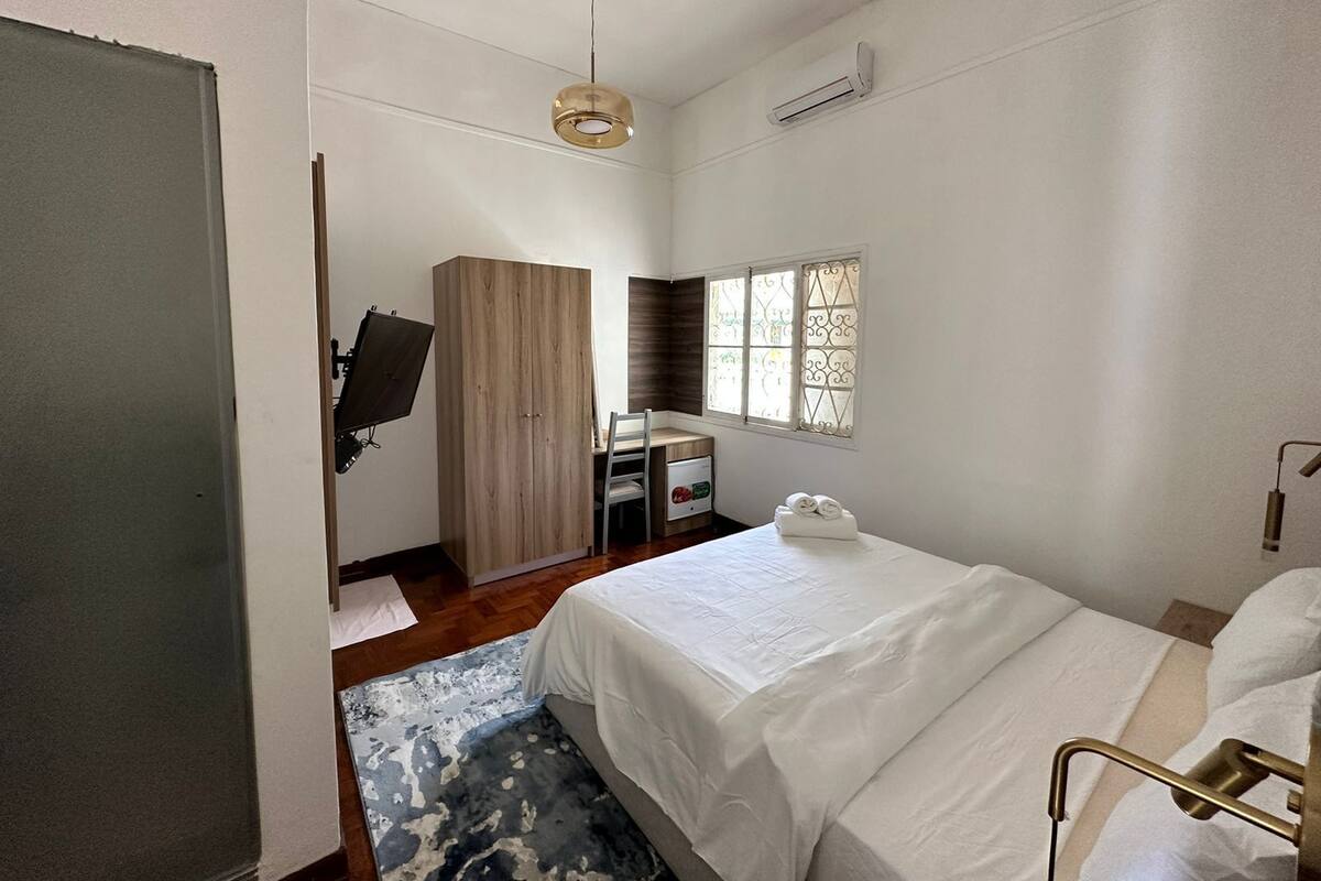 Une chambre à coucher comprenant un lit, un bureau, une armoire, une chaise et une fenêtre ornée de vitraux.