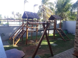 Explore a fun play area with multiple levels and platforms, featuring two shelters and a lush tropical setting.