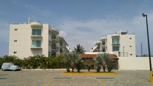 A parking area with a covered car and a building with balconies.