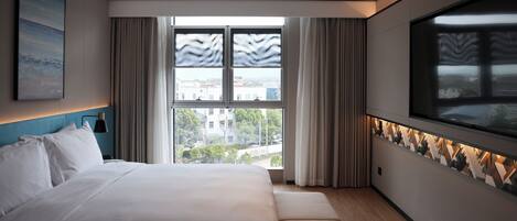 A modern hotel room with a large bed, a view of the city through floor-to-ceiling windows, and a decorative wall panel.
