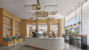 Een moderne hotel lobby met een centraal receptiebalie, een zithoek en grote ramen met uitzicht op de stad.