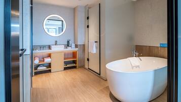 A modern bathroom with a freestanding bathtub, a round mirror, and a wooden vanity.