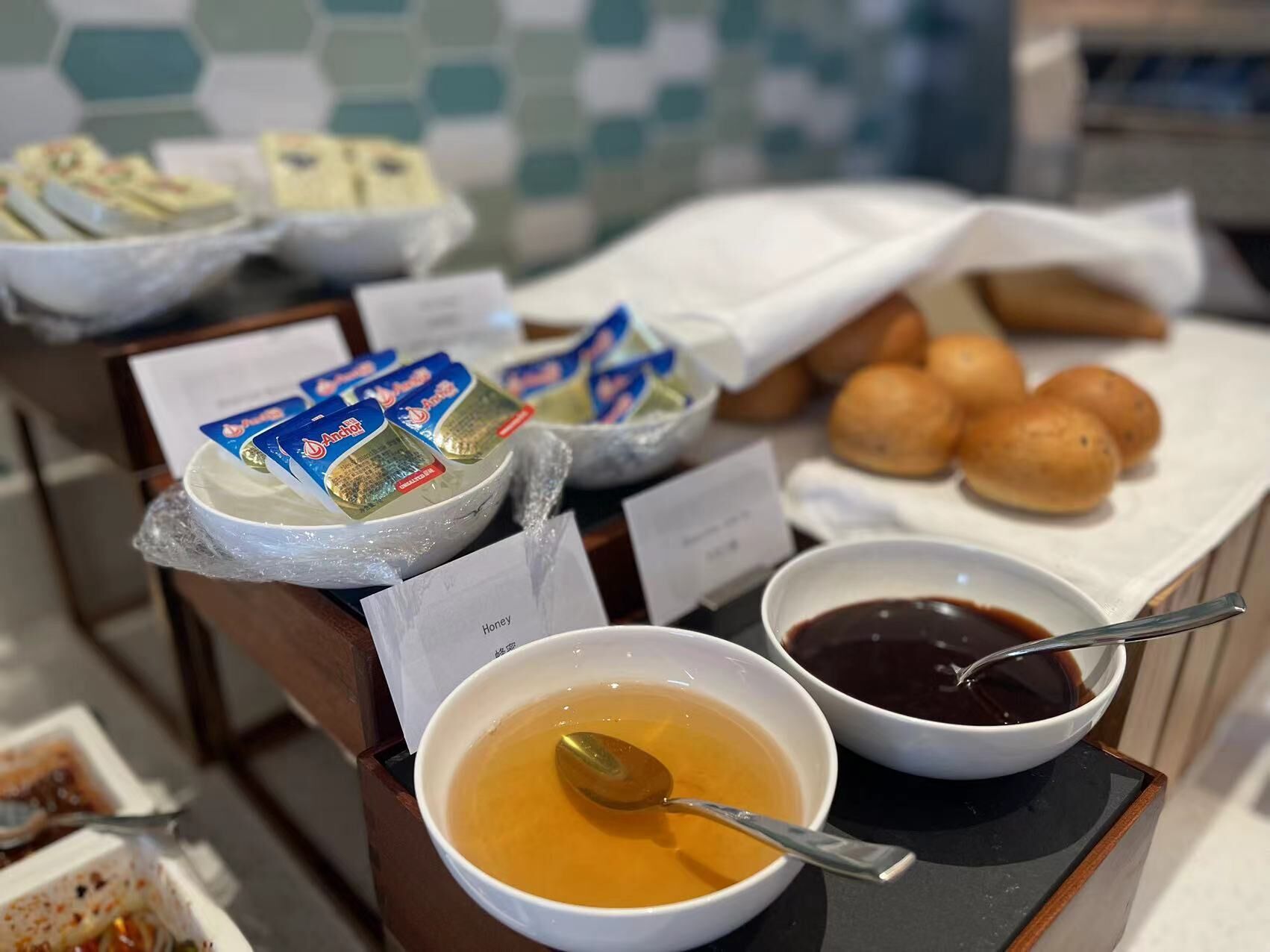 Ein Buffet mit verschiedenen Speisen, darunter Suppenschalen, Honig und Brötchen.
