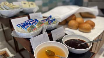 Ein Buffet mit verschiedenen Speisen, darunter Suppenschalen, Honig und Brötchen.