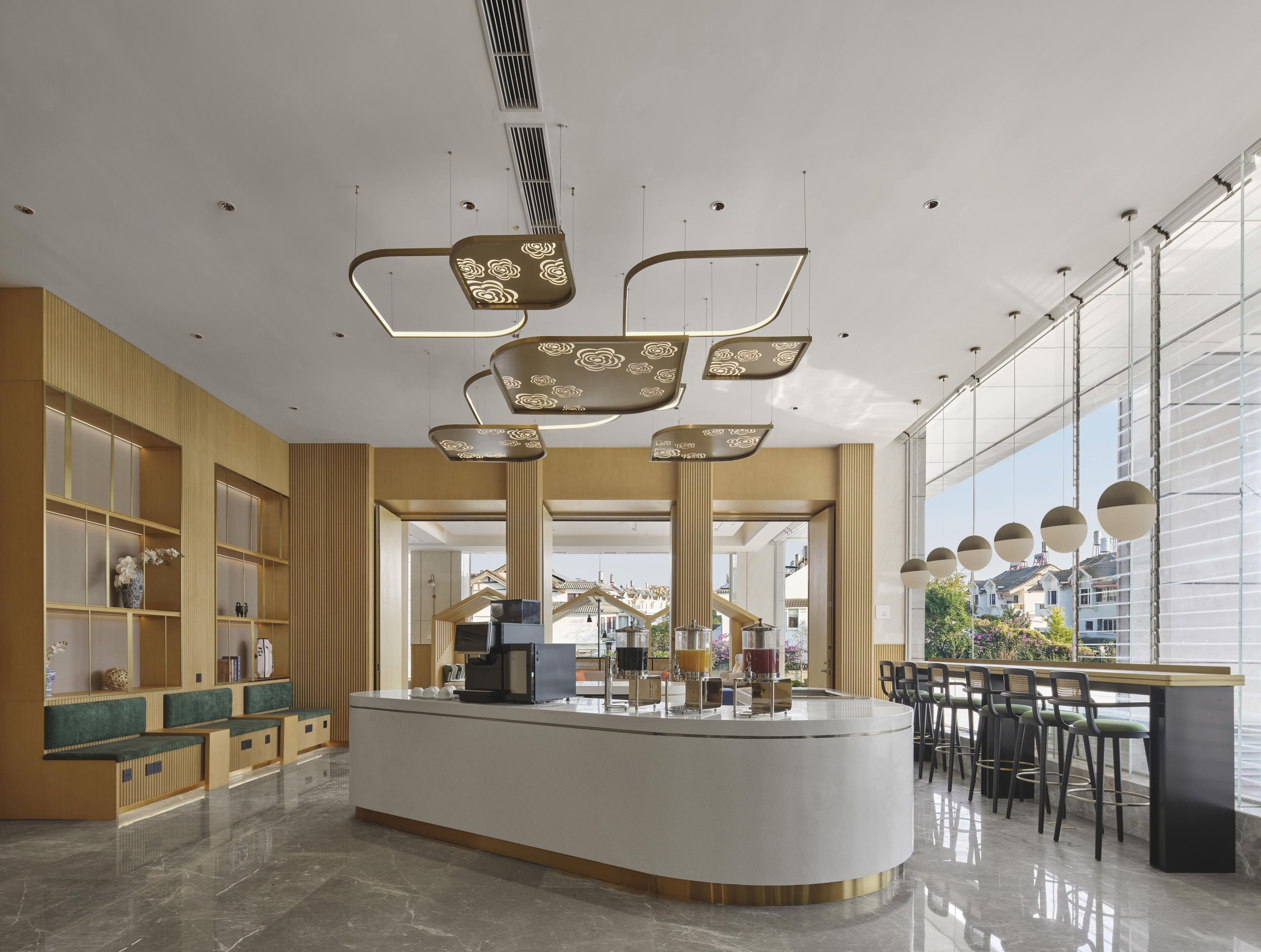 Un hall d’hôtel moderne doté d’un comptoir d’accueil central, d’un espace salon et de grandes fenêtres offrant une vue sur l’extérieur.