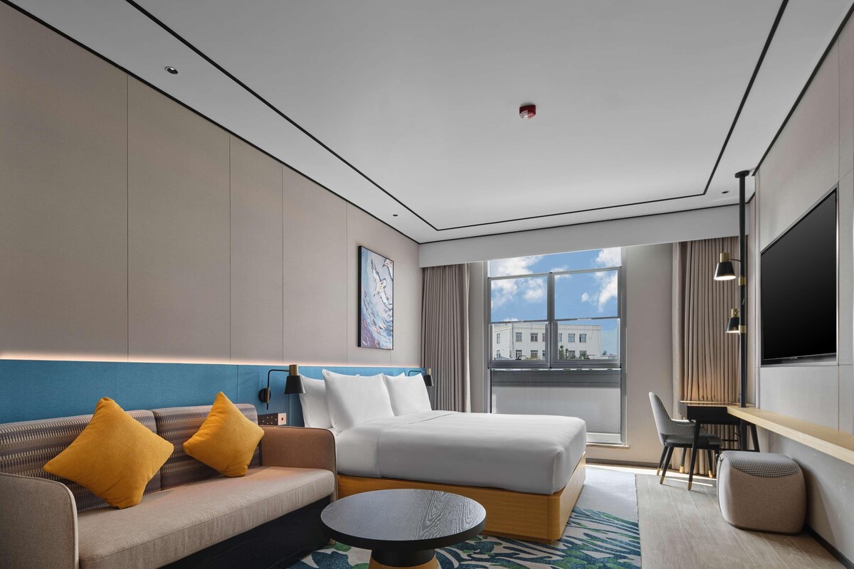 Une chambre d’hôtel moderne équipée d’un lit, d’un canapé et d’un espace bureau.