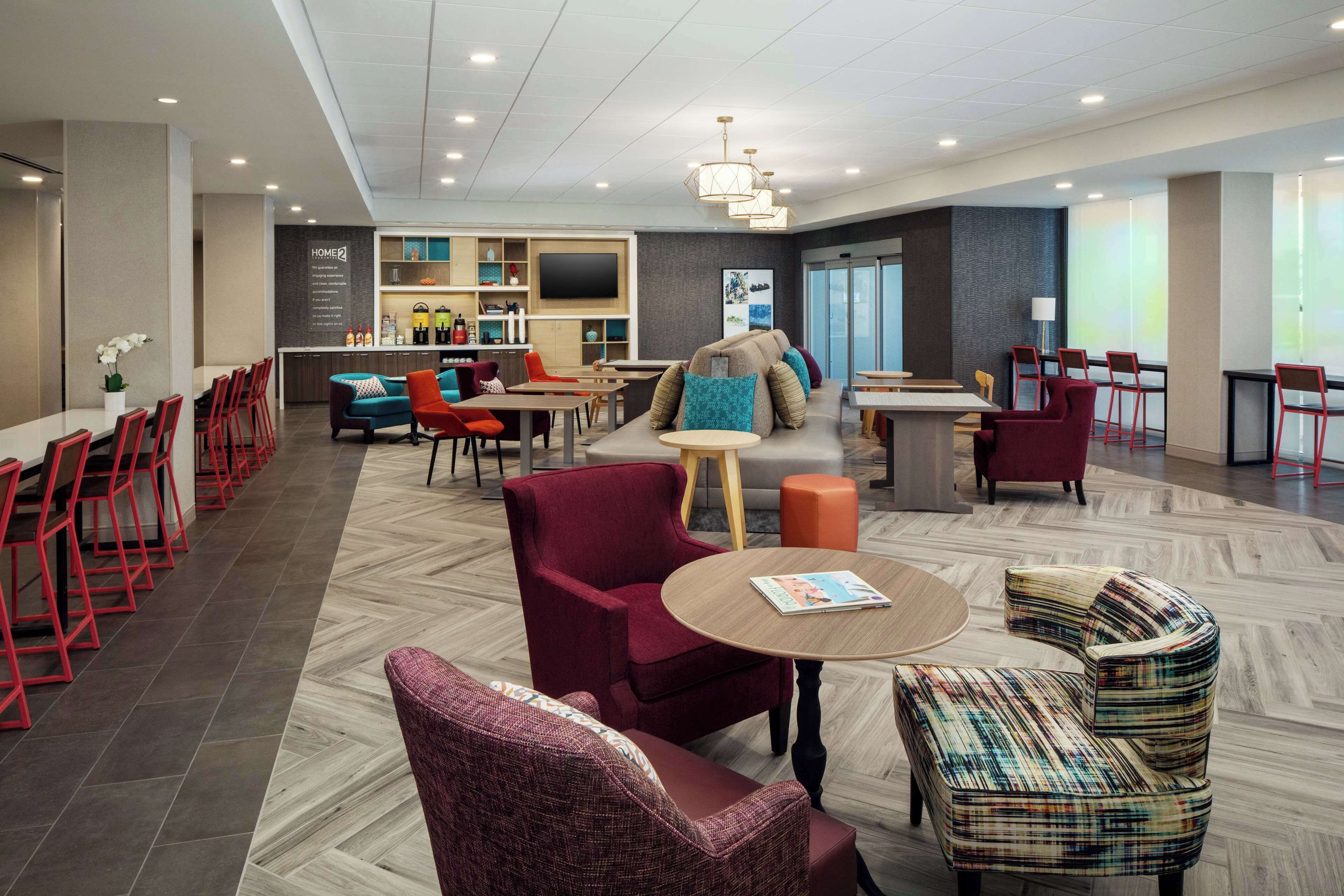 A modern hotel lobby with a bar, seating areas, and a television.
