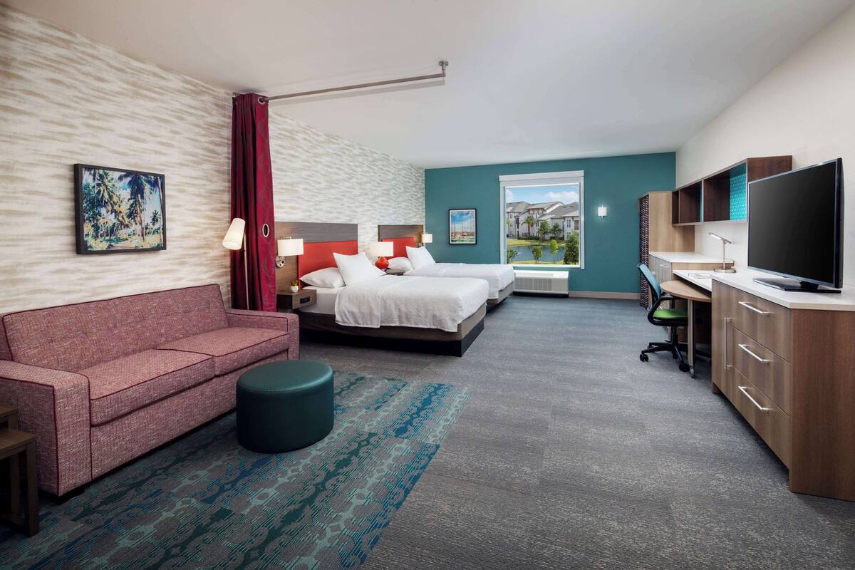 A hotel room with a bed, a sofa, a desk, and a TV.