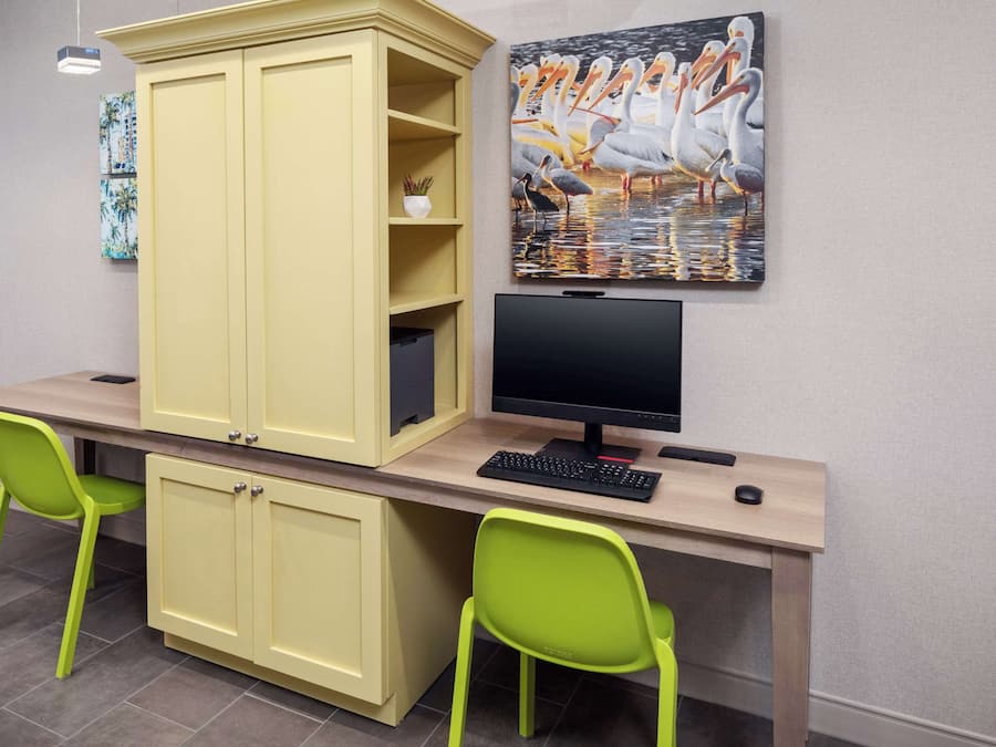 A study area with a desk, two green chairs, a computer, and a large cabinet.